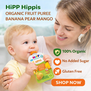 Woman holding a baby who is eating HiPP Hippis organic fruit puree, with promotional text about the product.