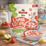 Holle Bio Lama Loops crispy cereals packaging on a wooden table with a bowl of cereal and fruits.