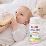 Baby drinking from a bottle with a Hipp Combiotik bottle in the foreground