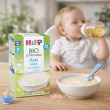 Hipp organic baby food packaging with a baby drinking from a cup in the background