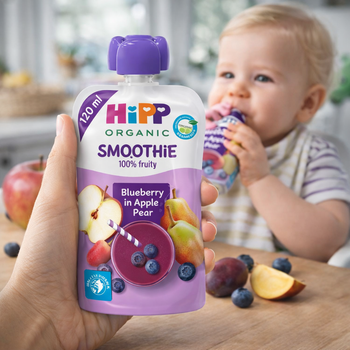Hipp Organic Smoothie bottle held by a hand with a baby drinking from another Hipp Organic Smoothie bottle in the background.