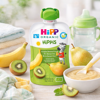 Hipp Organic Hippis baby food pouch with fruits and a bowl of baby food on a table.