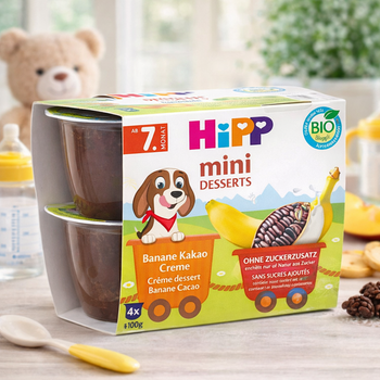 Hipp mini desserts packaging with a teddy bear and baby items in the background