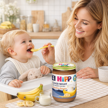 Woman feeding a baby with a spoon next to a jar of Hipp Good Night baby food.
