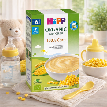 Hipp organic baby cereal box with baby bottle, bowl, and spoon on a table.