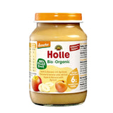 Jar of Holle organic baby food with apple, banana, and apricot on a white background