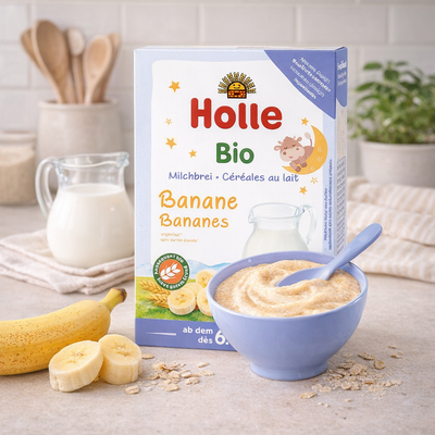Holle organic banana cereal packaging with a bowl of cereal and bananas on a table.
