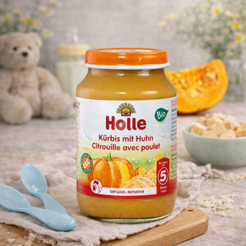 Jar of Holle baby food with pumpkins and a teddy bear in the background