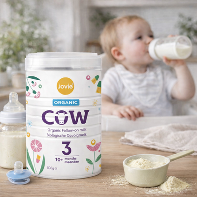 Jovie organic baby formula container with a child drinking from a bottle in the background
