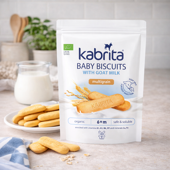 Kabrita baby biscuits with goat milk packaging on a table with cookies and milk.