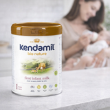 Kendamil bio nature first infant milk powder can with a blurred background of a woman holding a baby.