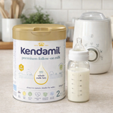 Kendamil premium follow-on milk powder can with a bottle and warmer on a kitchen counter.