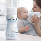 Kendamil follow-on milk bottle with a baby and mother in the background