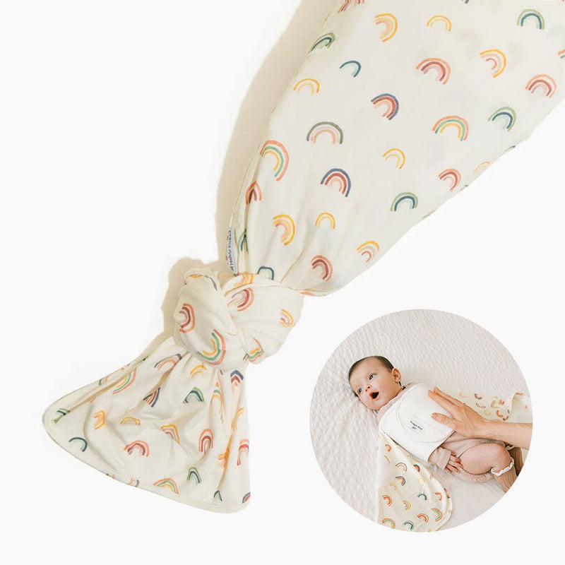 Rainbows Swaddle II swaddle blanket set with cream fabric, rainbow pattern, and matching cream snuggle band